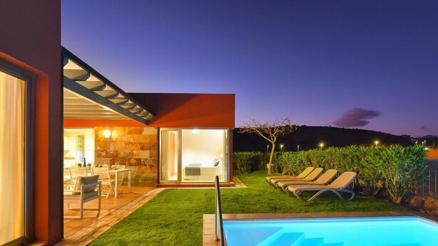 Ein modernes Haus mit Swimmingpool, Essbereich und gepflegtem Rasen.