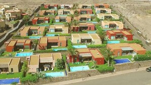 Ein Küstenresort mit mehreren Bungalows, jedes mit einem privaten Pool und Meerblick.