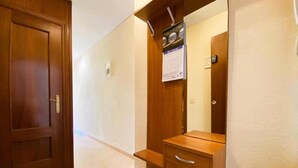 A hallway with a wooden door on the left, a wooden cabinet with drawers, and a calendar on the wall. - Apartamento Miramar Calpe (Calpe)