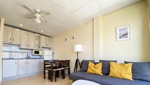 A compact living space with a kitchenette, a dining area, and a sofa with cushions. - Apartamento Miramar Calpe (Calpe)