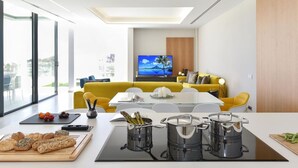 A modern kitchen with a dining area, a TV in the background, and a view of the city.