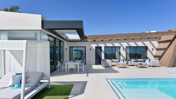 A modern outdoor pool area with a white lounge chair, a small table, and a pool.