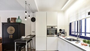 A modern kitchen with a central island, bar stools, a built-in oven, and a window overlooking the street. - Stunning private villa for 6 people with pool, A/C, WIFI, TV and patio (Maspalomas)