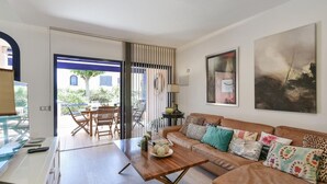 A living room with a wooden coffee table, a sofa with patterned cushions, a painting on the wall, and a view of the outside patio area. - Stunning private villa for 6 people with pool, A/C, WIFI, TV and patio (Maspalomas)