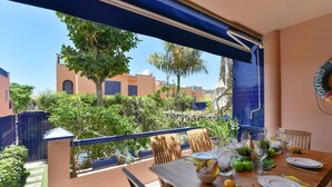 A dining area with a table set for two, a view of the neighborhood, and a blue awning. - Stunning private villa for 6 people with pool, A/C, WIFI, TV and patio (Maspalomas)