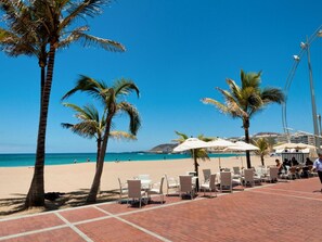 Une zone située en bord de mer, agrémentée de palmiers, de chaises de plage et de parasols.