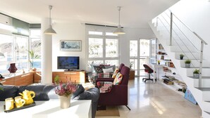 A spacious living area with a sofa, TV, and a staircase with bookshelves. - Nice apartment for 4 guests with WIFI, TV, terrace and pets allowed (Las Palmas De Gran Canaria)