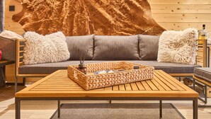 Ein gemütliches Zimmer mit einem Holztisch, einer Couch mit weichen Kissen und einem großen Fellteppich an der Wand.