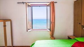 A room with a bed, a window with curtains, a wardrobe, and a mirror.