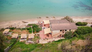 Una propiedad costera con una casa grande, un patio con mobiliario exterior y vistas a la playa.