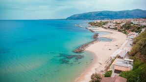 Un pueblo costero con playa de arena, costa rocosa y edificios residenciales.