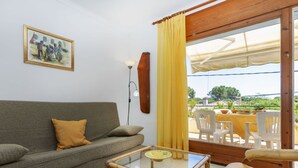 A living room with a sofa, a glass coffee table, and a dining area with chairs and a table. - Cosy apartment in villa for 5 people with WIFI, TV and terrace (Torroella De Montgrí)