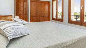 A bedroom with a bed, wooden wardrobe, and a balcony view. - Cosy apartment in villa for 5 people with WIFI, TV and terrace (Torroella De Montgrí)