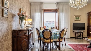 Un comedor con candelabro, televisor y vistas por la ventana.