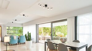 Ein geräumiger Wohnbereich mit Esstisch, Stühlen und einem großen Fenster mit Blick auf einen Garten.