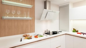 Eine moderne Küche mit weißen Schränken, einer Holzwand und einer Arbeitsfläche mit verschiedenen Gegenständen, darunter Eier, Gemüse und eine Bratpfanne.