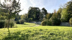 Een grasveld met een stenen muur en bomen.