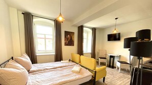 Een hotelkamer met een tweepersoonsbed, een bureau, een stoel en een aan de muur bevestigde televisie.