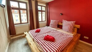 A bedroom with a wooden bed, red walls, and a window with curtains. - Beautiful apartment for 6 people with WIFI, TV, patio and pets allowed (Zittau)