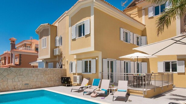 Un espace aménagé au bord de la piscine, avec une piscine à l’eau cristalline, des chaises longues et des parasols.