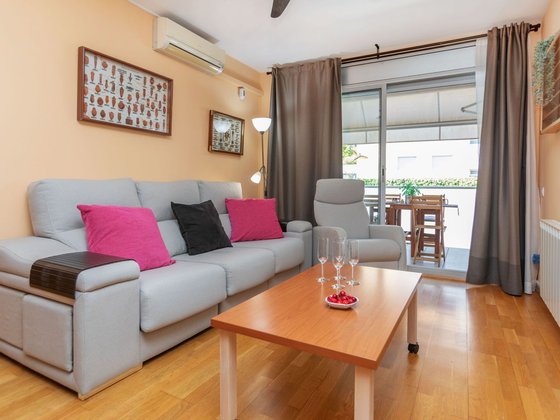 Uma sala de estar moderna com um sofá cinza, uma mesa de centro de madeira e uma área de jantar com mesa e cadeiras.