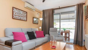 Een moderne woonkamer met een grijze bank, een houten salontafel en een eethoek met een tafel en stoelen.