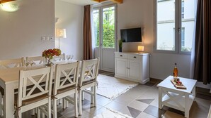 Un coin repas avec une table et des chaises, un téléviseur fixé au mur et une fenêtre avec des rideaux.