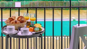 A breakfast tray with croissants, orange juice, and a plate of fruit on a balcony overlooking a pool. - Lovely apartment for 6 guests with pool, WIFI, TV and balcony (Baden)