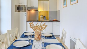 A compact kitchen with white cabinets, a microwave, and a coffee maker. There is a dining table set with plates and glasses. - Lovely apartment for 6 guests with pool, WIFI, TV and balcony (Baden)
