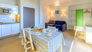 Un espace de vie compact comprenant une kitchenette, un coin repas et un coin salon.