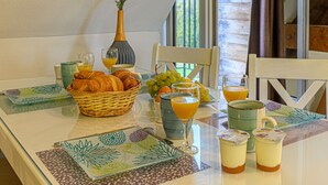 Ein Frühstückstisch mit Croissants, Trauben, Orangensaft und einer Vase mit Blumen.