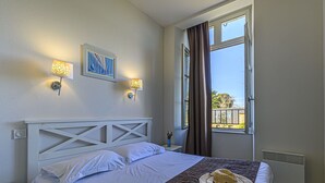 A hotel room with a bed, two wall-mounted lamps, a window with curtains, and a painting on the wall. - Lovely apartment for 5 guests with WIFI, pool and TV (Baden)