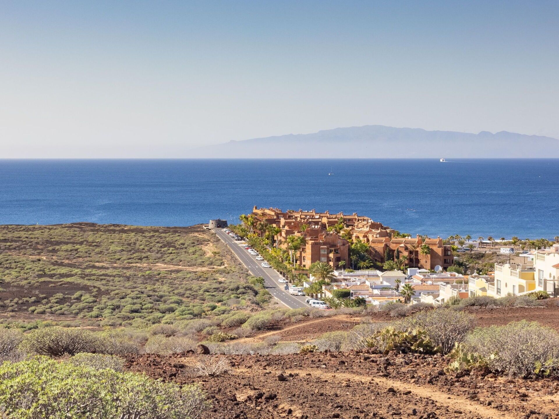 A coastal town with a historic fort, a main road, and a view of the sea.