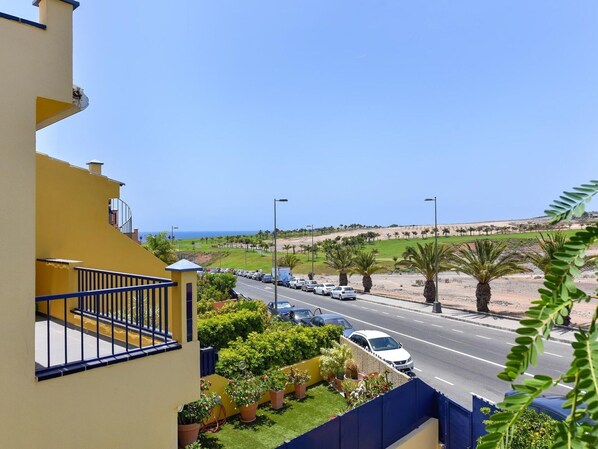 Ein Wohngebiet mit einer Straße, parkenden Autos und Blick auf das Meer.