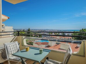 Varanda com mesa e cadeiras, com vista para o horizonte urbano e uma piscina.