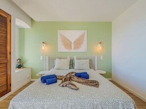 A bedroom with a bed, pillows, a blanket, a wall art piece, and two wall-mounted lights.