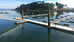 A marina with docks, a sailboat, and a building on a hill. - Douarnenez, Proche de la Plage des Sables Blancs à Tréboul (Douarnenez)