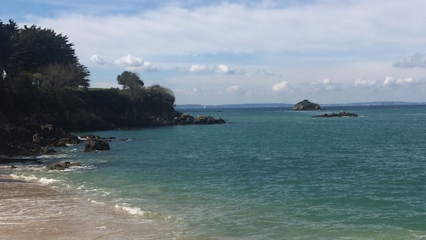 A beach with clear turquoise water, waves gently lapping at the shore, and rocky outcrops in the background. - Douarnenez, Proche de la Plage des Sables Blancs à Tréboul (Douarnenez)