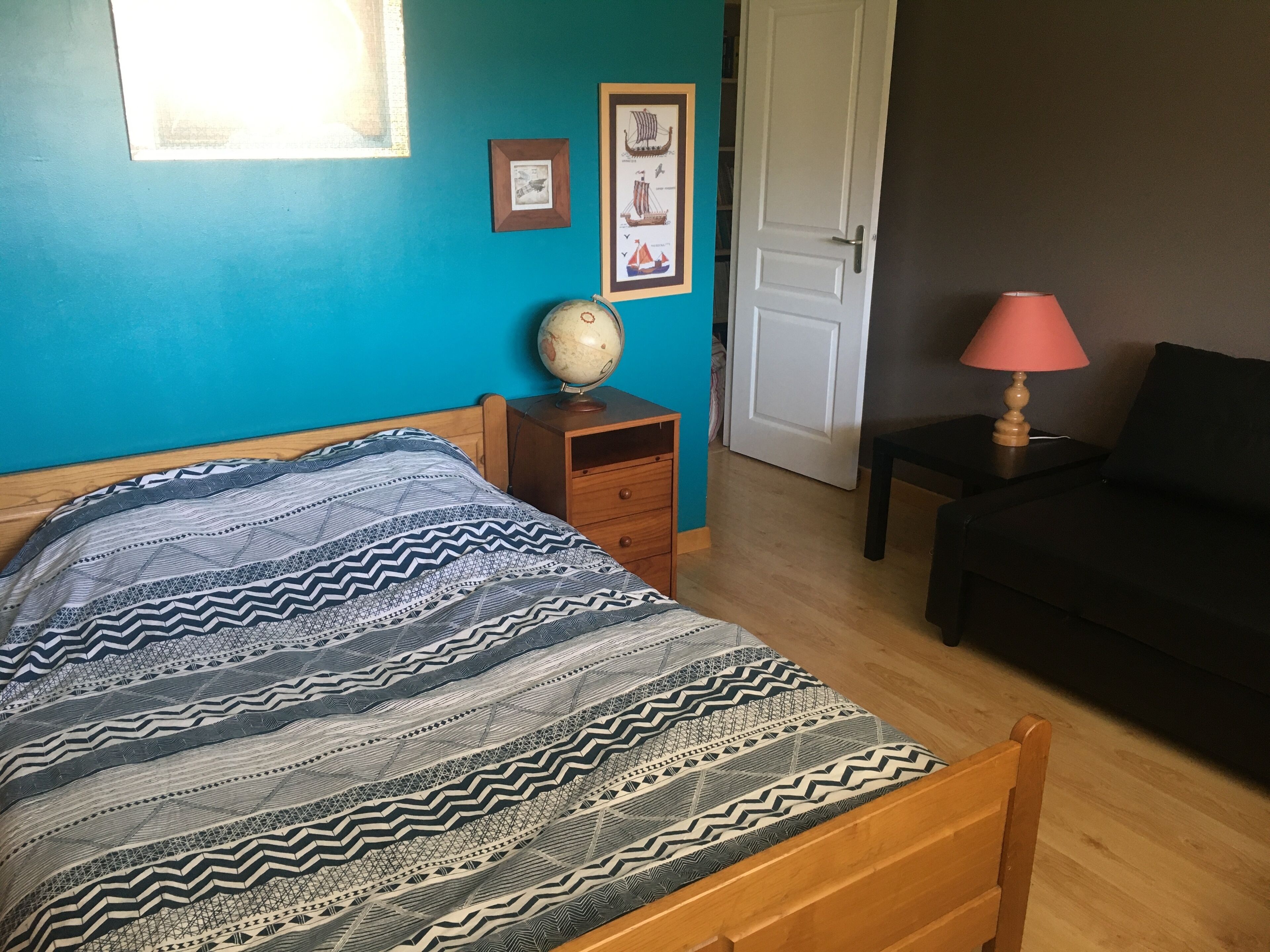 Une chambre à coucher avec un lit, une table de chevet, un globe terrestre et une lampe.