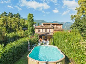 Relax by the serene pool surrounded by lush greenery and a mountainous backdrop.