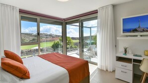 Un dormitorio con cama, escritorio, silla y televisor.