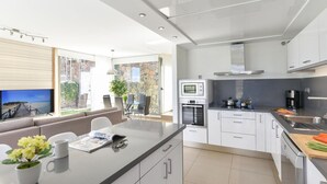 Una cocina moderna con armarios blancos, horno empotrado, microondas y cafetera.