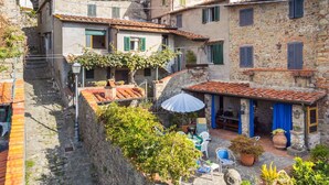 A traditional stone building with a courtyard, outdoor seating, and a view of the surrounding hillside. - Nice apartment for 4 people with WIFI, A/C, pets allowed and panoramic view (Capannori)