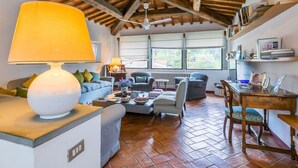 A cozy living room with a fireplace, a dining area, and a large window providing a view of the outdoors. - Beautiful private villa for 8 guests with pool, A/C, WIFI, TV, patio and panoramic view (Greve In Chianti)