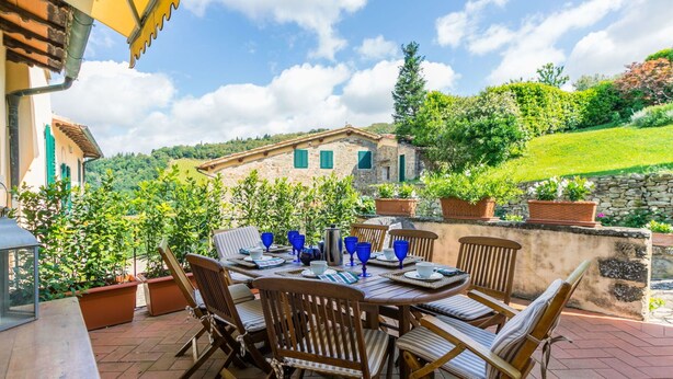 An outdoor patio with a round table set for four, surrounded by wooden chairs with striped cushions. - Beautiful private villa for 8 guests with pool, A/C, WIFI, TV, patio and panoramic view (Greve In Chianti)
