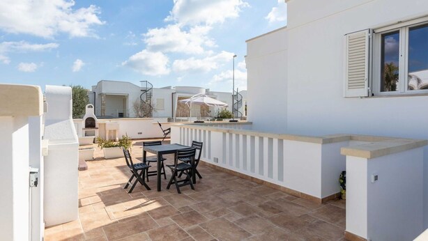 A rooftop patio with a table and chairs, a barbecue grill, and a view of the surrounding buildings. - Lovely apartment in villa for 4 people with A/C, TV and patio (Salve)