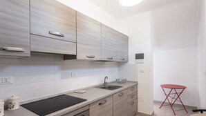 A modern kitchen with light wood cabinets, a stainless steel oven, and a black induction cooktop. - Lovely apartment in villa for 4 people with A/C, TV and patio (Salve)