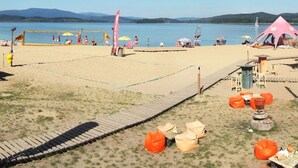Un terrain de beach-volley avec un filet, des chaises de plage et une tente.