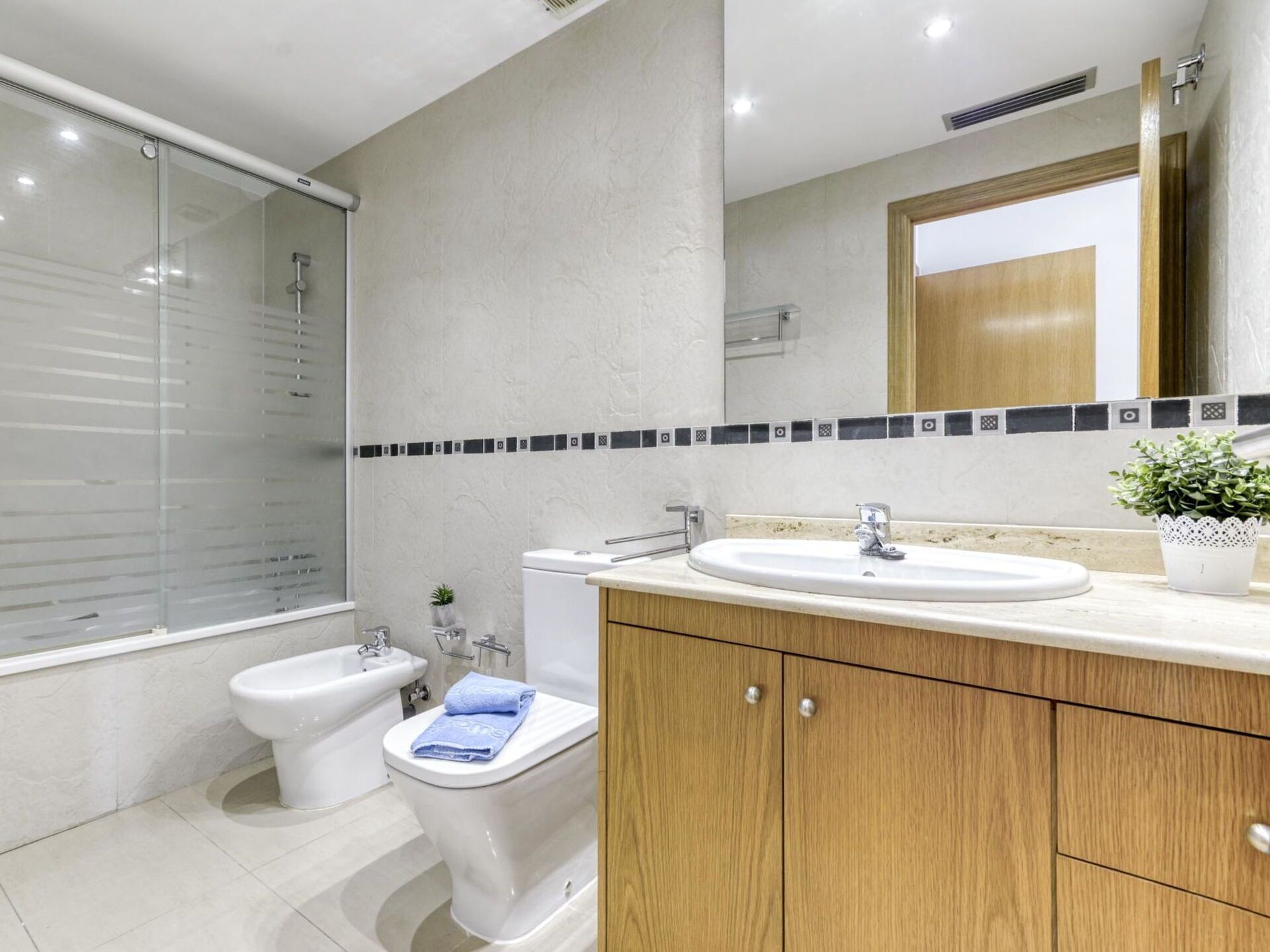 A modern bathroom with a shower, toilet, bidet, and vanity.