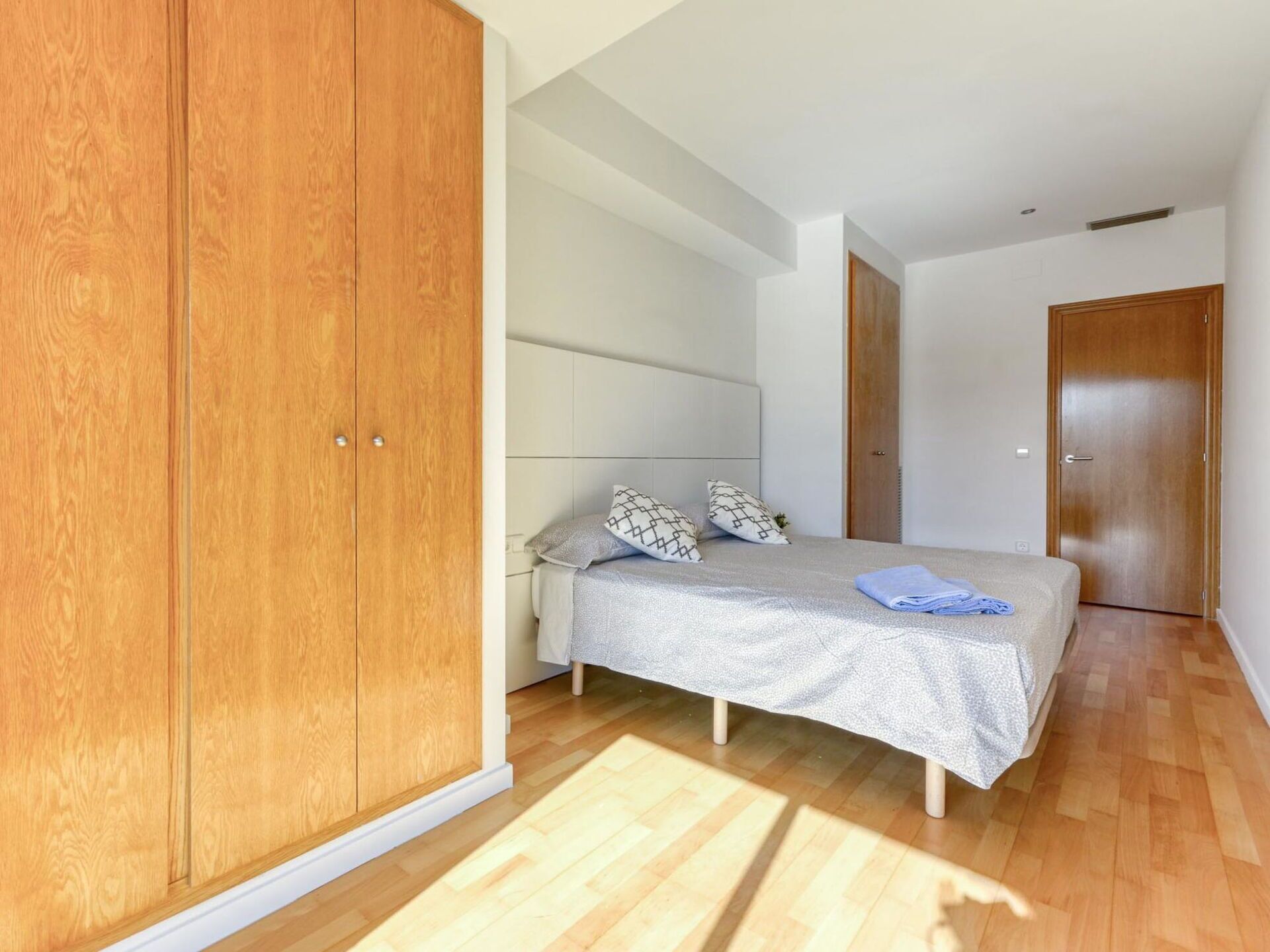 Un dormitorio con cama, armario de madera y una puerta.